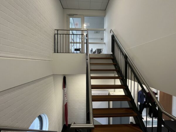 Trapopgang in een modern kantoor aan de Niels Bohrweg met zicht op een glazen deur en een ruimte met bureaus.